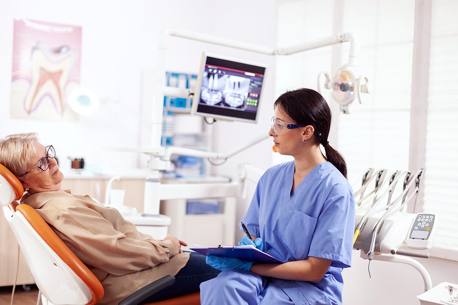 Older woman having a discussion with a dentist about her treatment options.